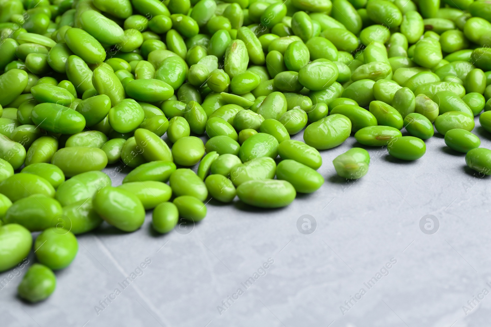 Photo of Fresh edamame soybeans on grey textured table, closeup