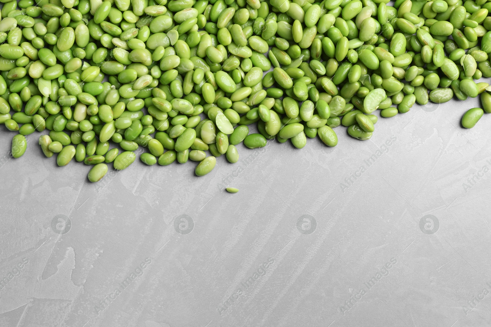 Photo of Fresh edamame soybeans on grey textured table, top view. Space for text