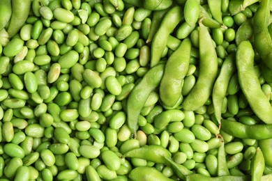 Fresh edamame beans and pods as background, top view