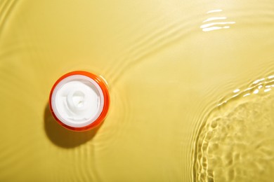 Cosmetic product. Jar with cream in water on yellow background, top view. Space for text