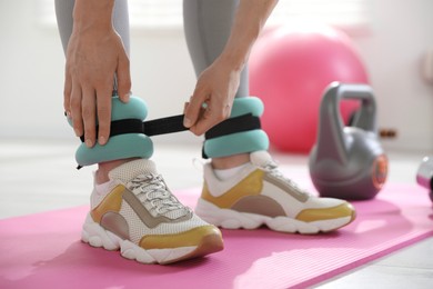 Woman putting on ankle weights indoors, closeup