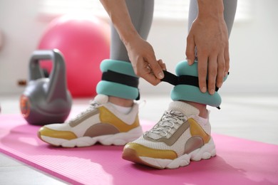 Woman putting on ankle weights indoors, closeup