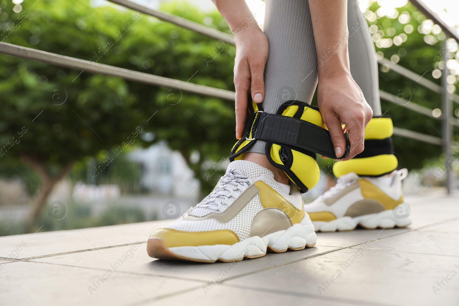 Photo of Woman putting on ankle weights outdoors, closeup