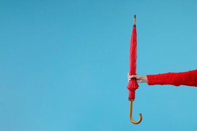 Photo of Woman with red umbrella on light blue background, closeup. Space for text