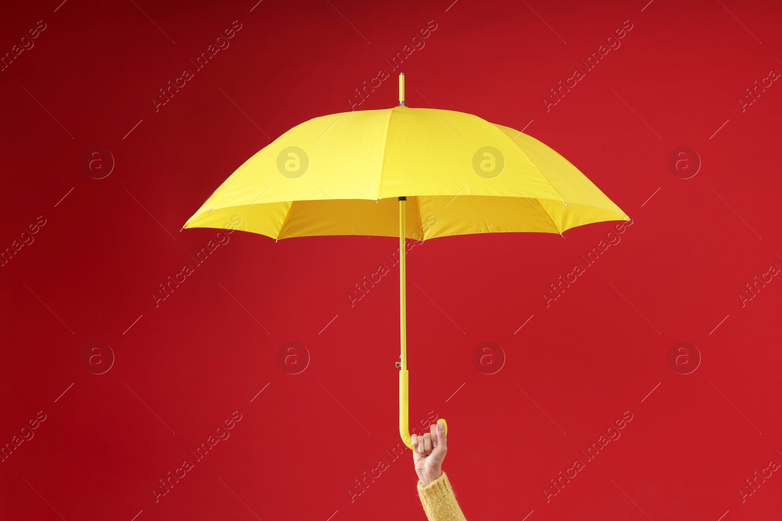 Photo of Woman with yellow umbrella on red background, closeup