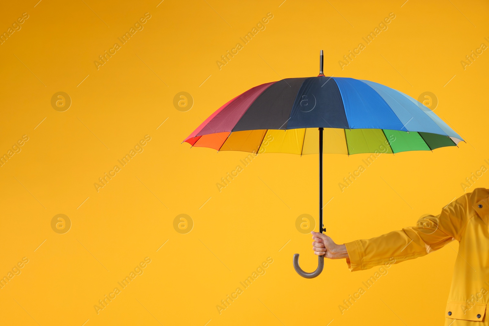 Photo of Woman with colorful umbrella on yellow background, closeup. Space for text