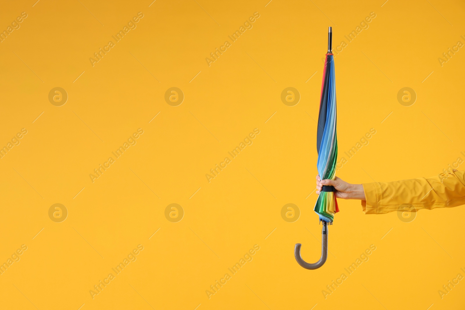 Photo of Woman with colorful umbrella on yellow background, closeup. Space for text