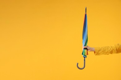 Woman with colorful umbrella on yellow background, closeup. Space for text