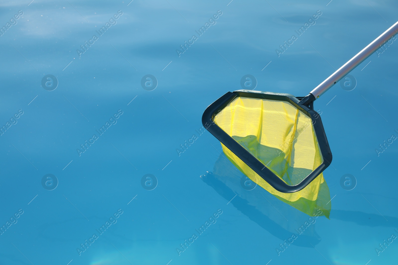 Photo of Cleaning swimming pool with skimmer net on sunny day