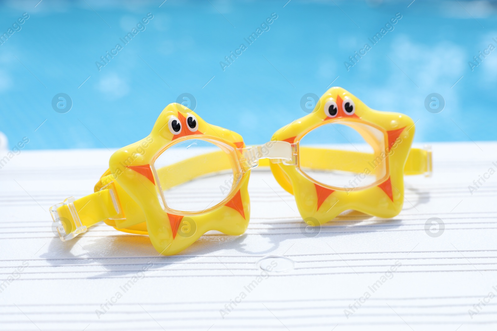 Photo of Cute swim goggles near swimming pool, closeup