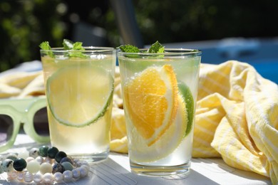 Tasty cocktail in glasses and sunglasses near swimming pool outdoors