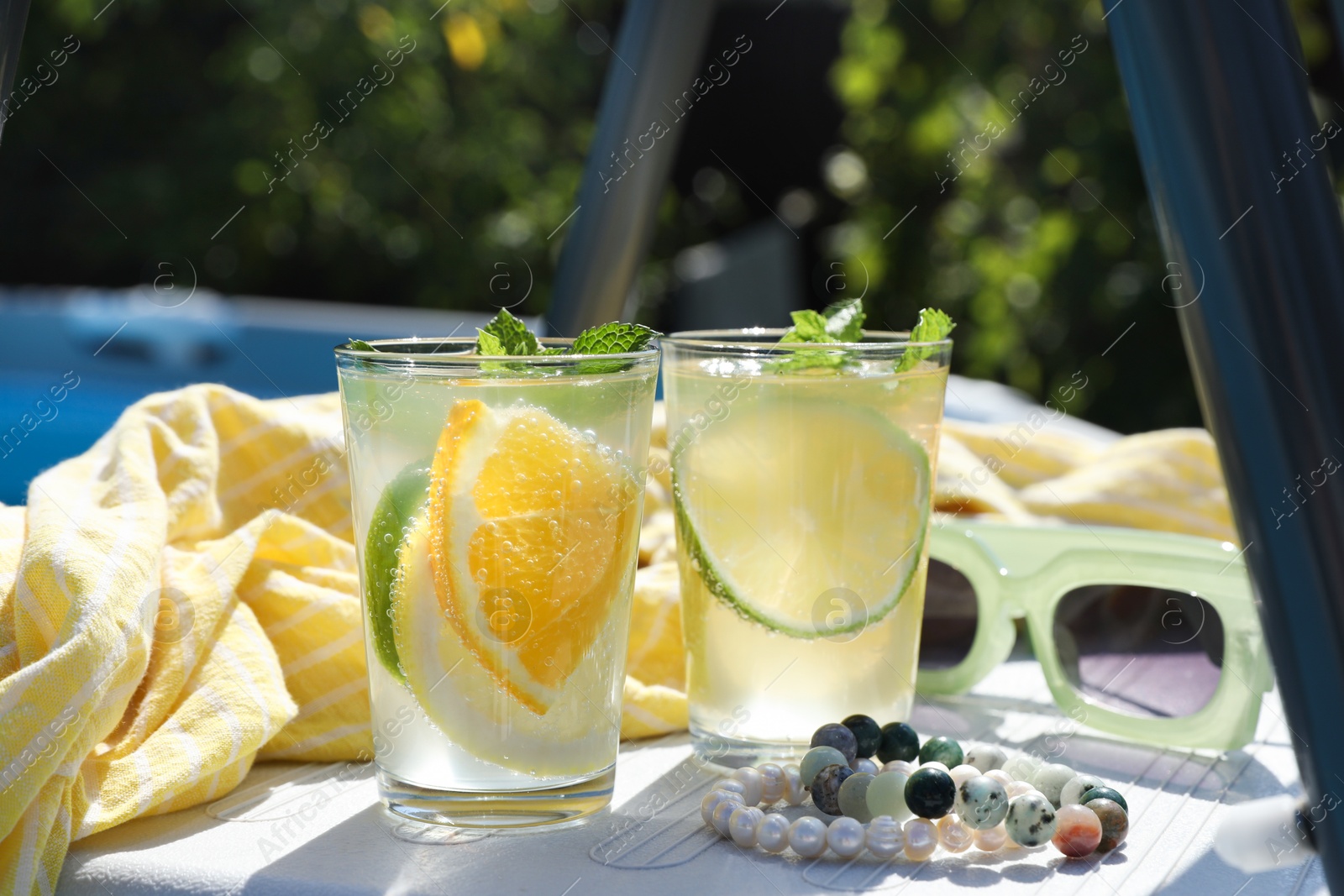 Photo of Tasty cocktail in glasses and sunglasses near swimming pool outdoors