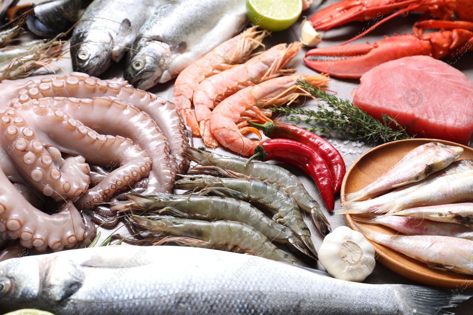 Photo of Many different sea food, garlic, chili pepper and thyme on table, closeup