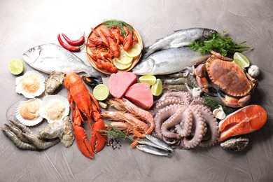 Many different sea food, herbs and lime on grey textured table, flat lay