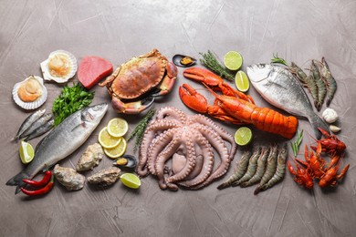 Photo of Many different sea food, herbs, lemon and lime on grey textured table, flat lay