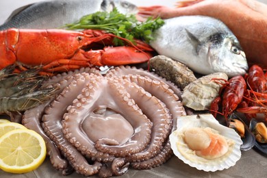 Many different sea food and lemon on grey textured table, closeup