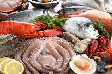 Many different sea food, herbs and lemon on table, closeup