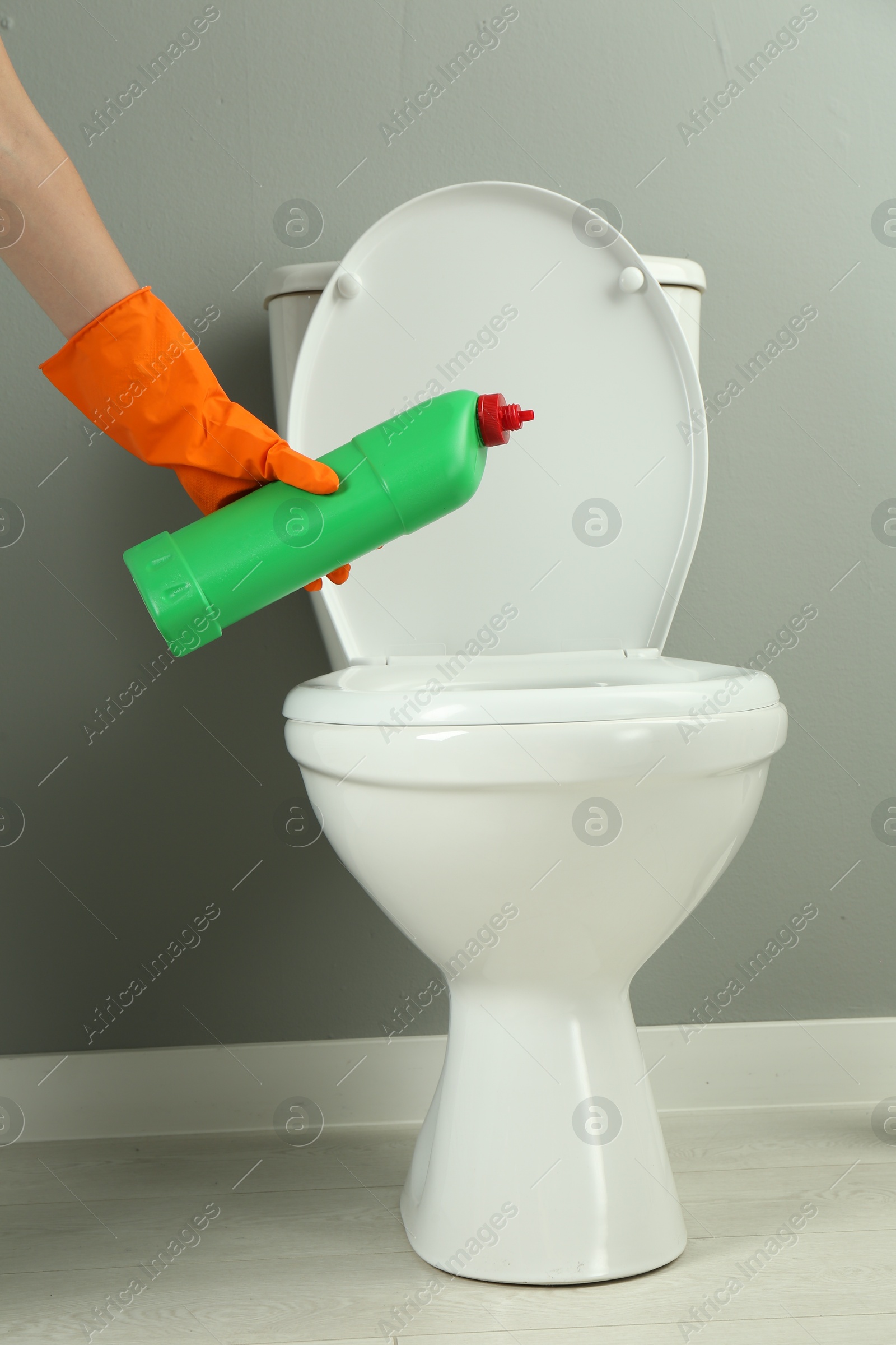 Photo of Woman cleaning toilet with detergent in bathroom, closeup