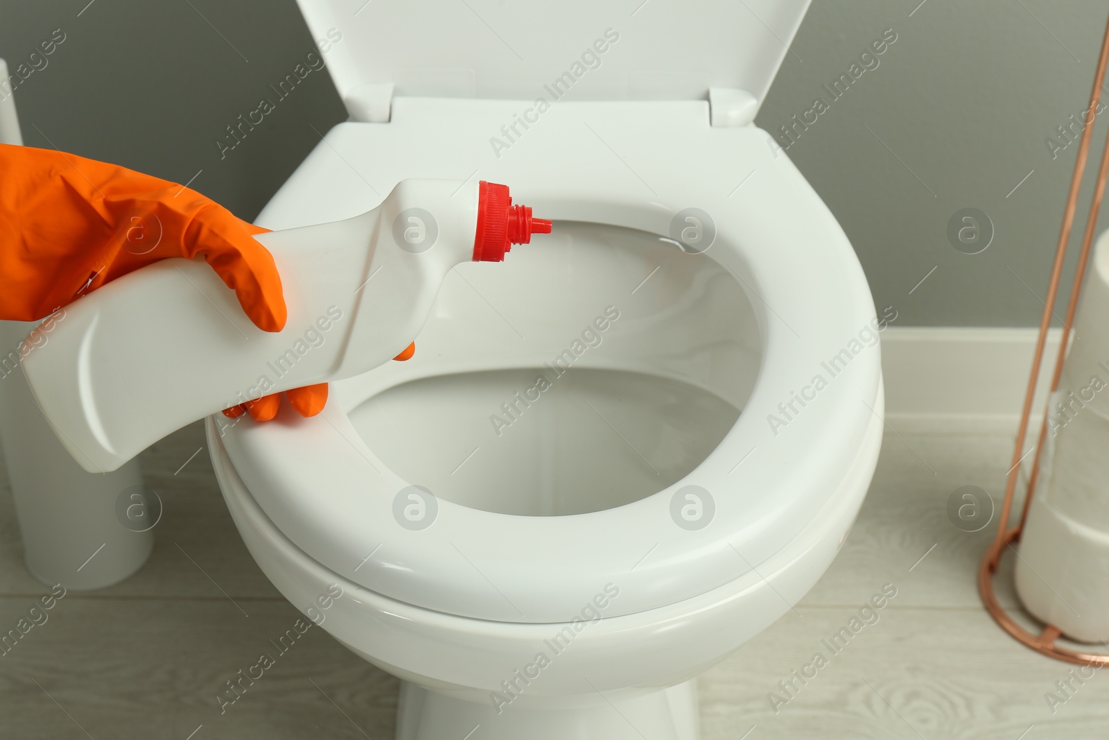 Photo of Woman cleaning toilet with detergent in bathroom, closeup