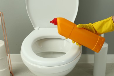 Photo of Woman cleaning toilet with detergent in bathroom, closeup