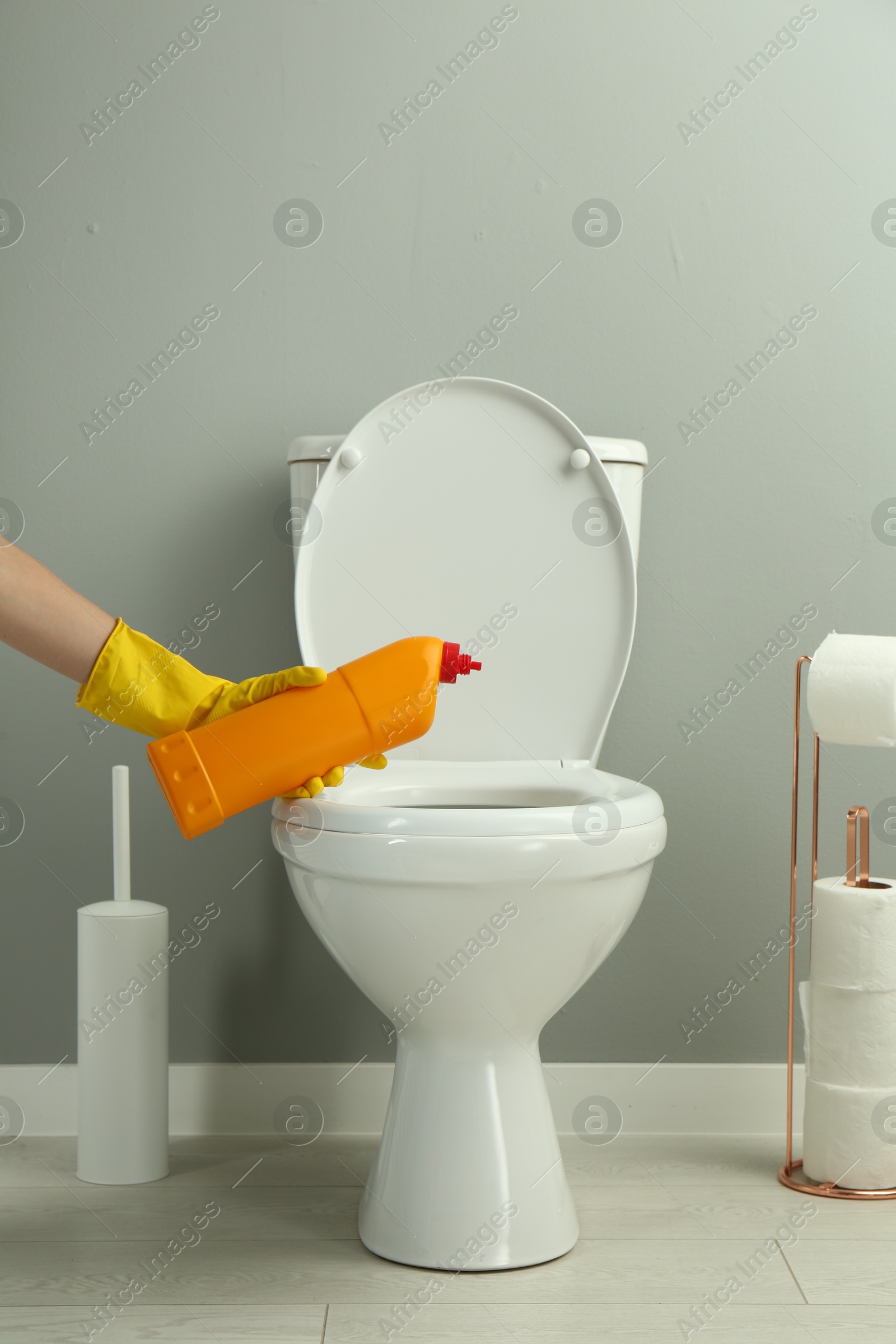 Photo of Woman cleaning toilet with detergent in bathroom, closeup