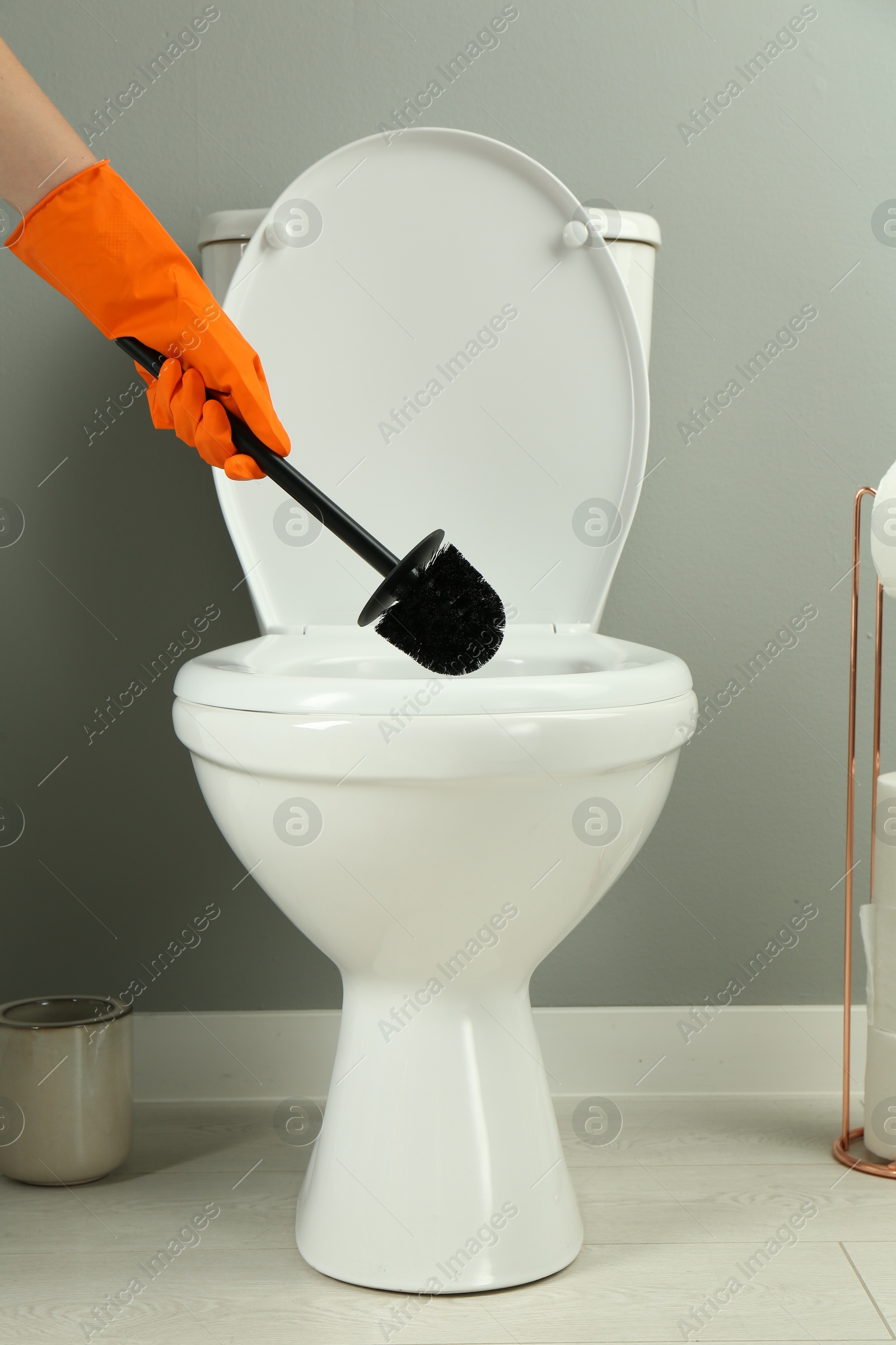 Photo of Woman cleaning toilet with brush in bathroom, closeup