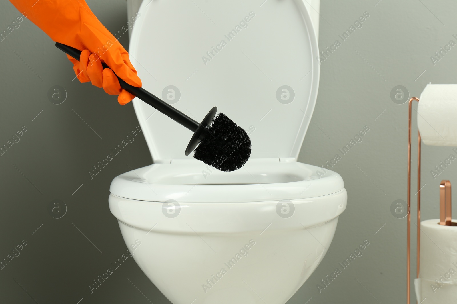 Photo of Woman cleaning toilet with brush in bathroom, closeup