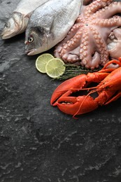 Photo of Sea food. Fresh raw octopus, fish and lobster on black table, flat lay. Space for text