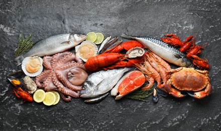 Fresh fish and different sea food on black table, top view