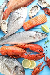 Different sea food on light blue wooden table, flat lay