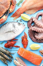 Different sea food on light blue wooden table, flat lay