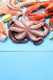 Different sea food on light blue wooden table, flat lay. Space for text