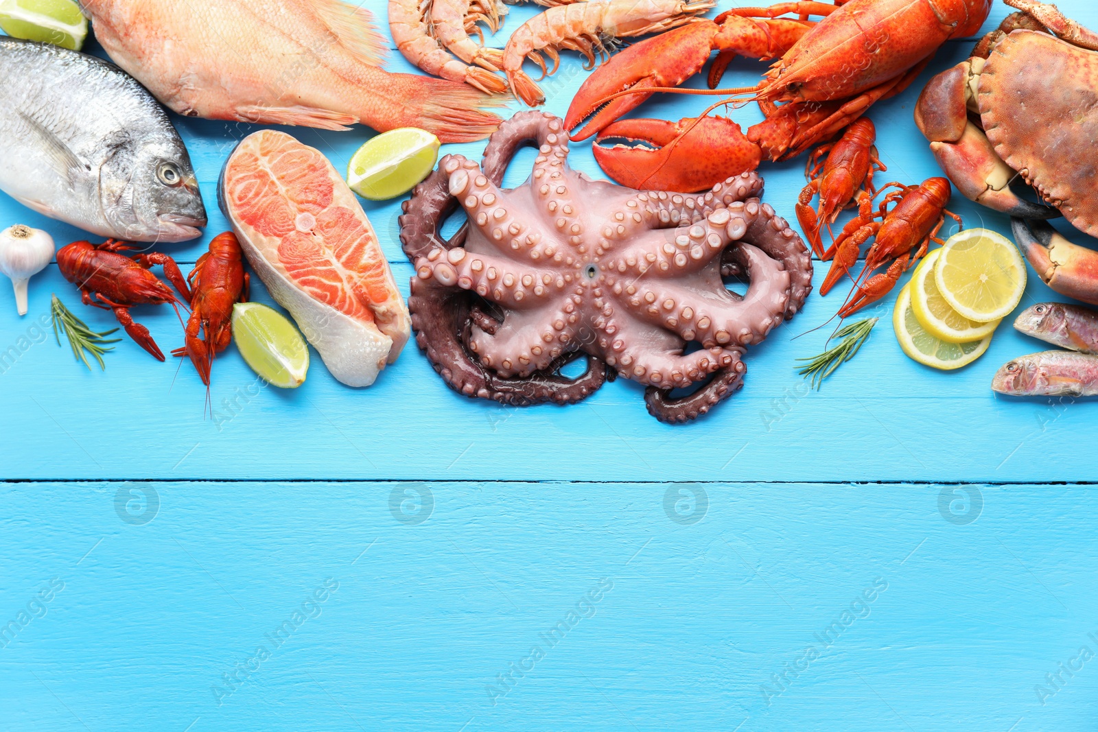 Photo of Different sea food on light blue wooden table, flat lay. Space for text