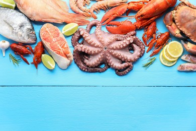 Different sea food on light blue wooden table, flat lay. Space for text