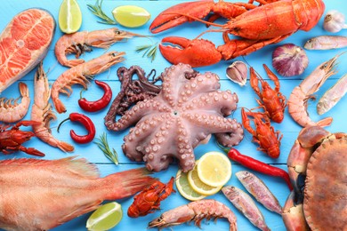 Different sea food on light blue wooden table, flat lay