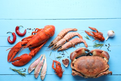 Different sea food on light blue wooden table, flat lay