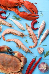 Different sea food on light blue wooden table, flat lay