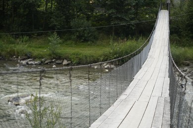 Photo of View of wooden suspension bridge over mountain river