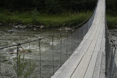 Photo of View of wooden suspension bridge over mountain river