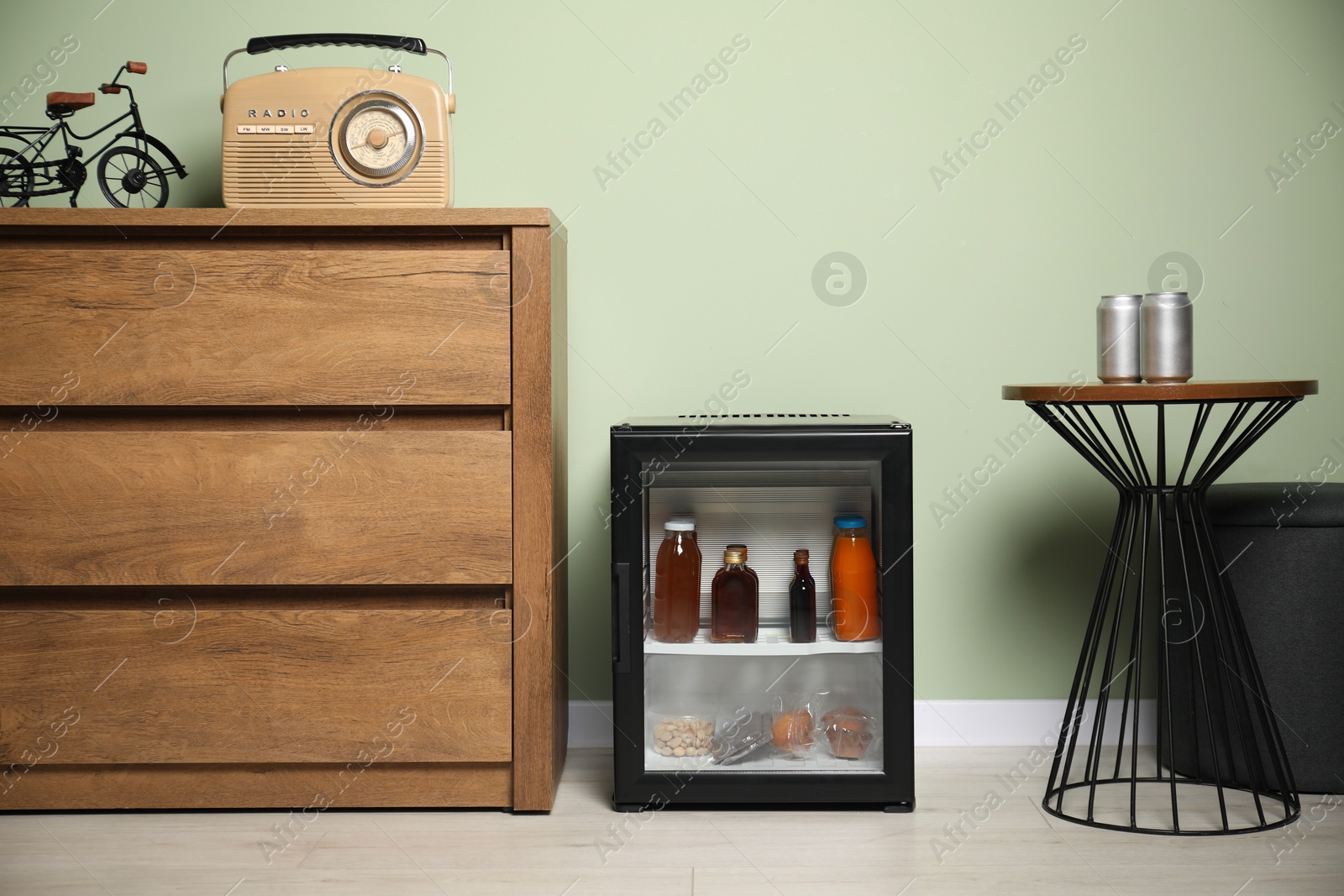 Photo of Mini refrigerator with different drinks and snacks indoors