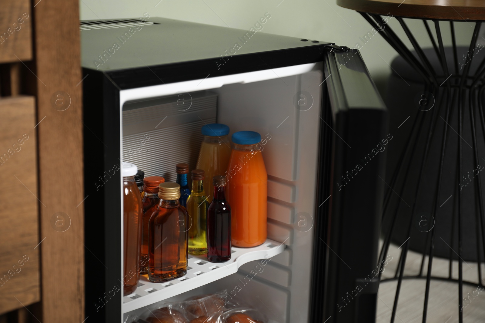 Photo of Mini refrigerator with different drinks and snacks indoors