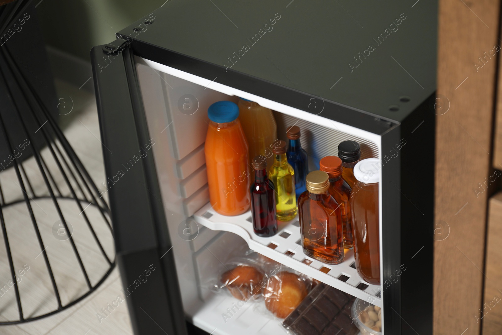 Photo of Mini refrigerator with different drinks and snacks indoors