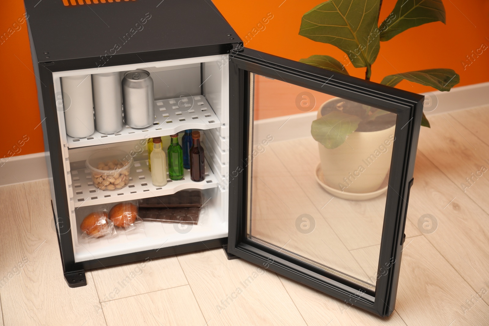 Photo of Mini refrigerator with different drinks and snacks indoors