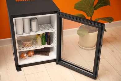 Mini refrigerator with different drinks and snacks indoors