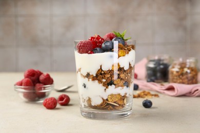 Photo of Tasty yogurt with fresh berries, granola and mint in glass on gray textured table