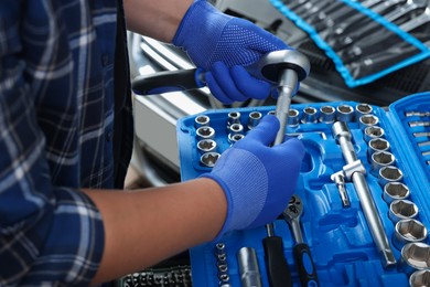 Photo of Auto mechanic with torque wrench at automobile repair shop, closeup