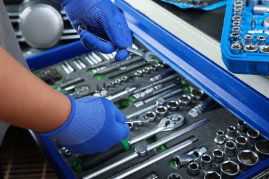 Auto mechanic with different tools at automobile repair shop, closeup