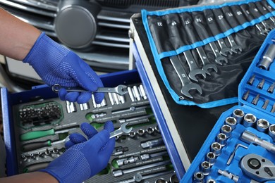 Auto mechanic with different tools at automobile repair shop, closeup