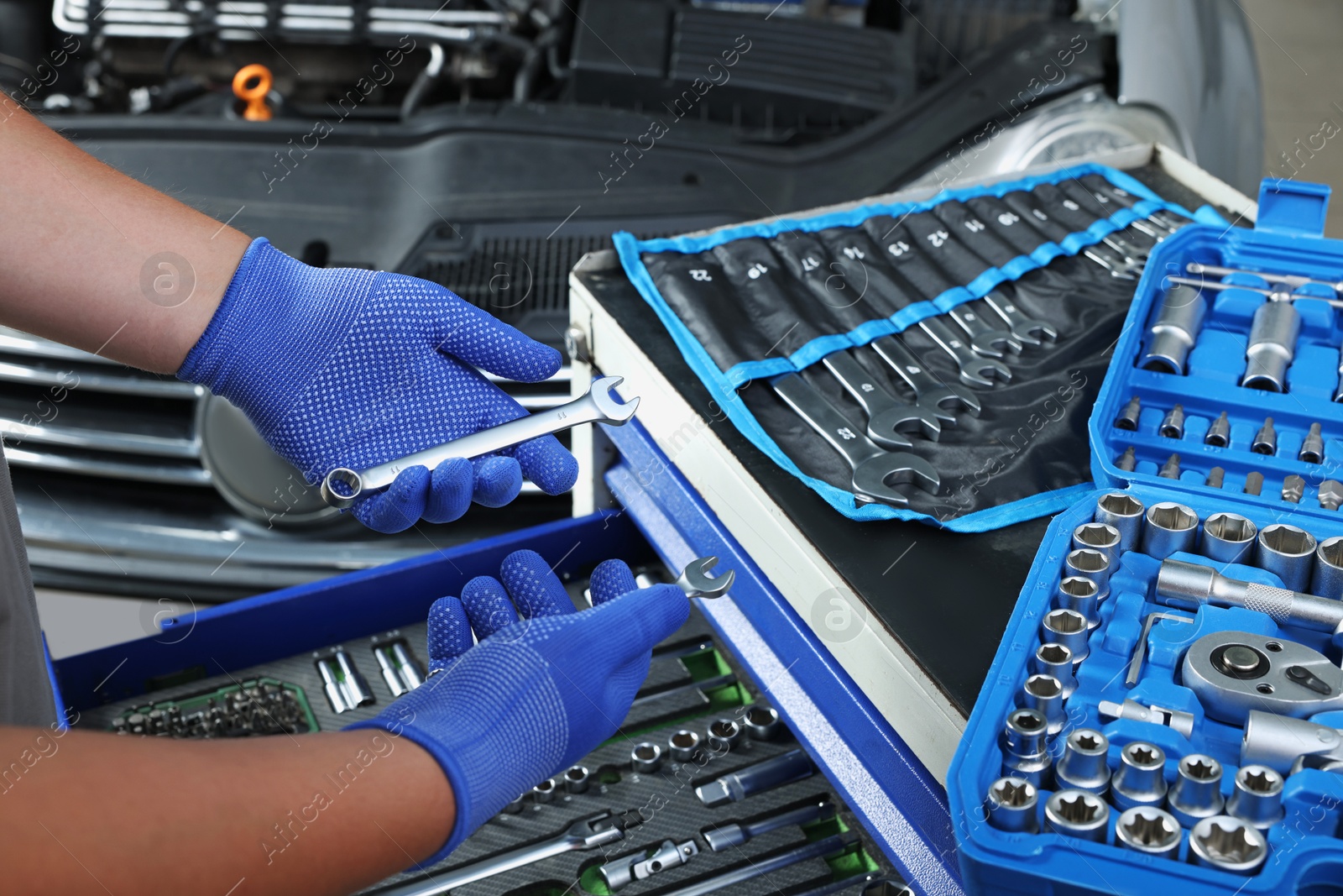 Photo of Auto mechanic with different tools at automobile repair shop, closeup