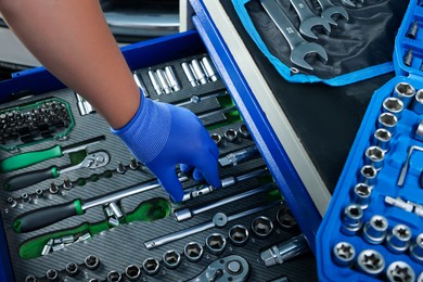 Auto mechanic with different tools at automobile repair shop, closeup